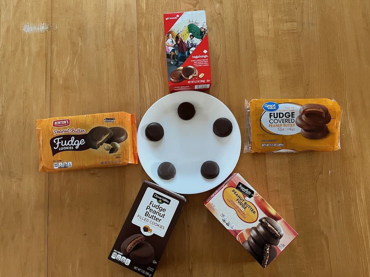 Assortment of generic girl scout fudge-covered cookies and packaging displayed on a wooden surface.