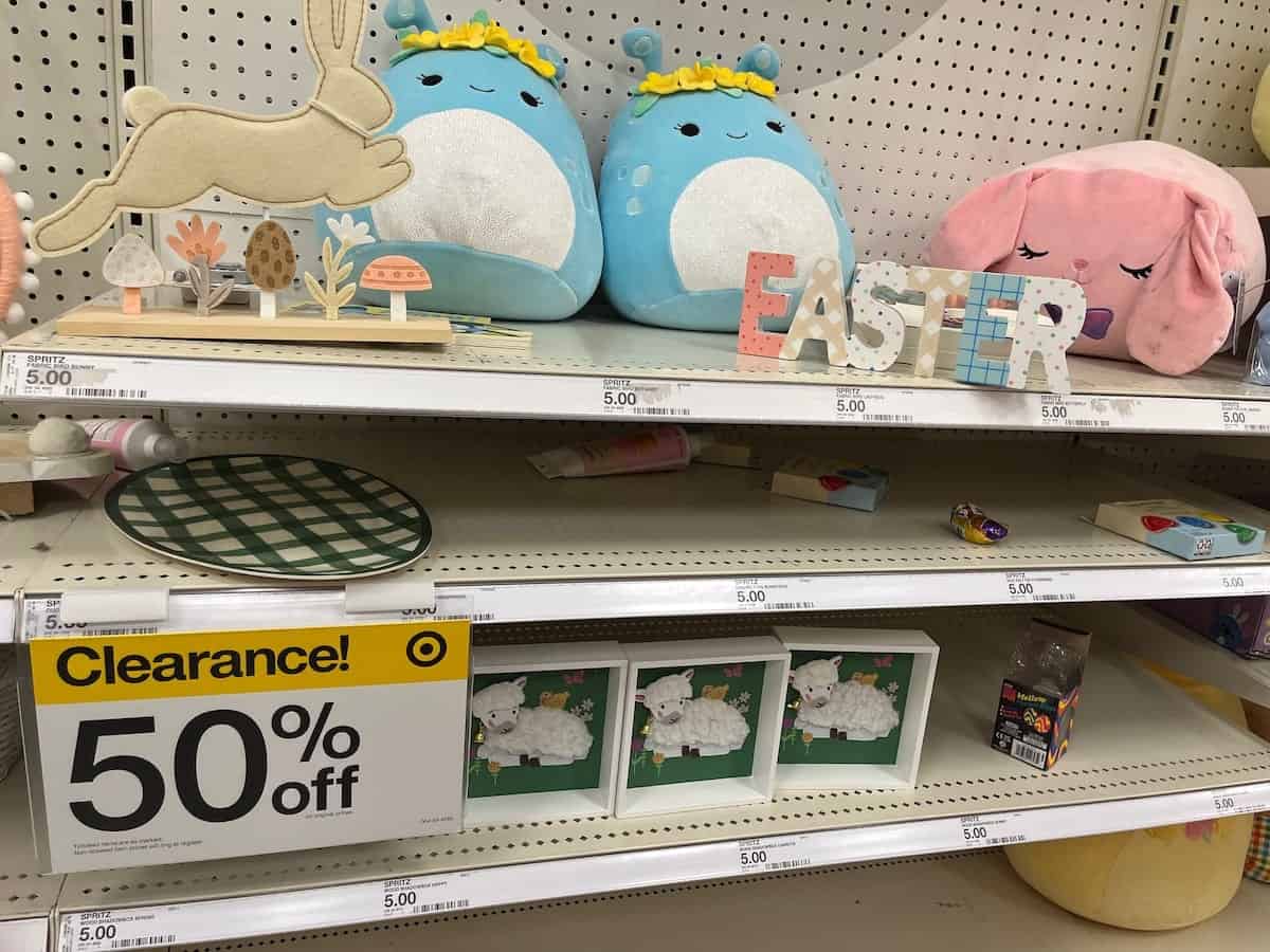 Easter-themed decorations and stuffed animals on a store shelf marked with a 50% off clearance sign for after-Easter sales.
